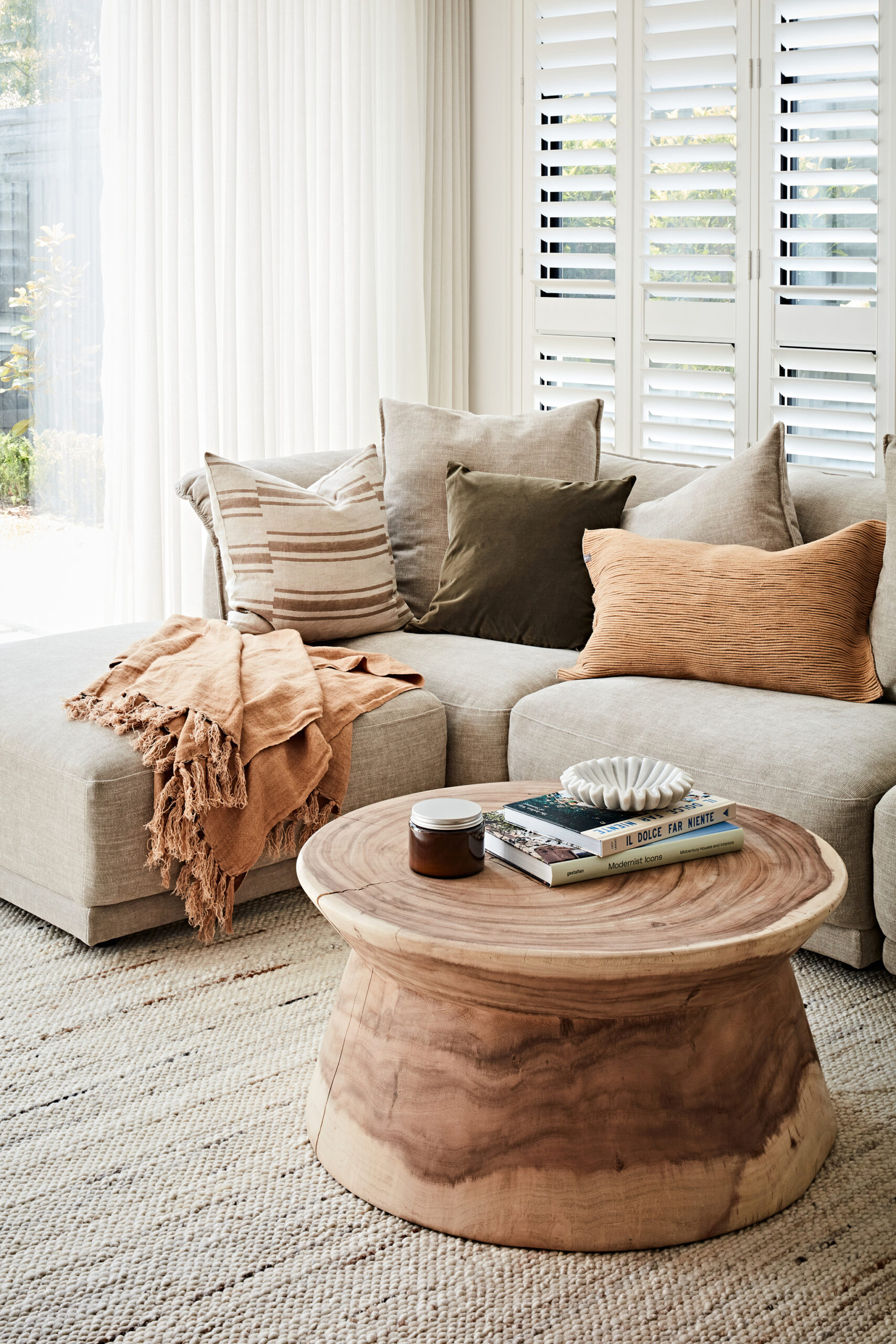 Neutral living room with linen sofa, timber coffee table, layered cushions and white shutters in a Hampton East family home styled by Lisa Hunter Interiors.
