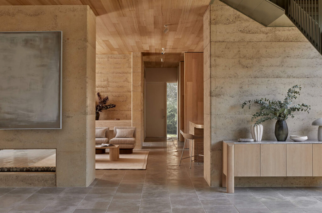 Contemporary Australian interior featuring textured stone walls, timber ceilings, natural stone flooring, minimalist cabinetry and neutral furnishings.
